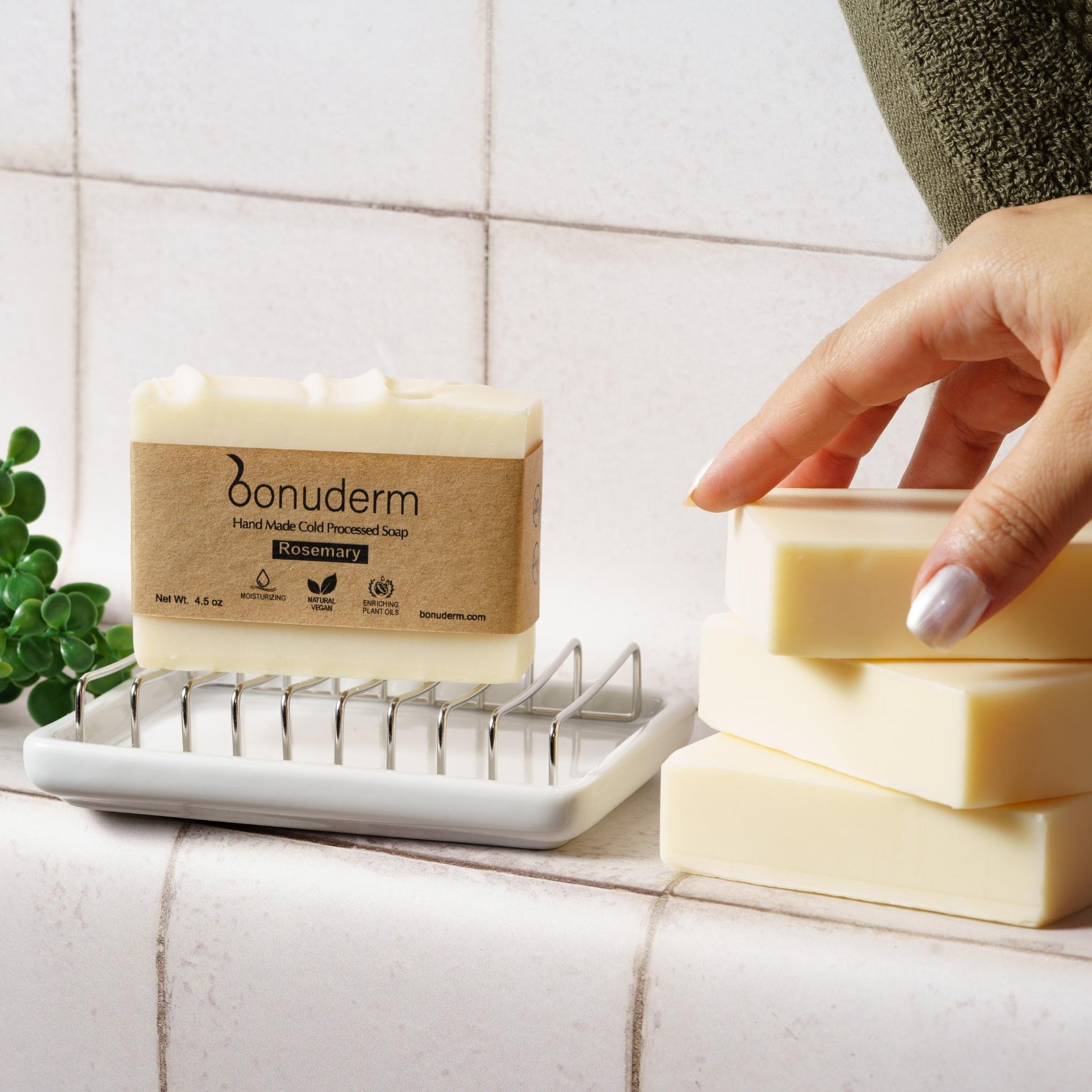 Bonuderm handmade soap on a bar soap holder in a tiled bathroom counter.