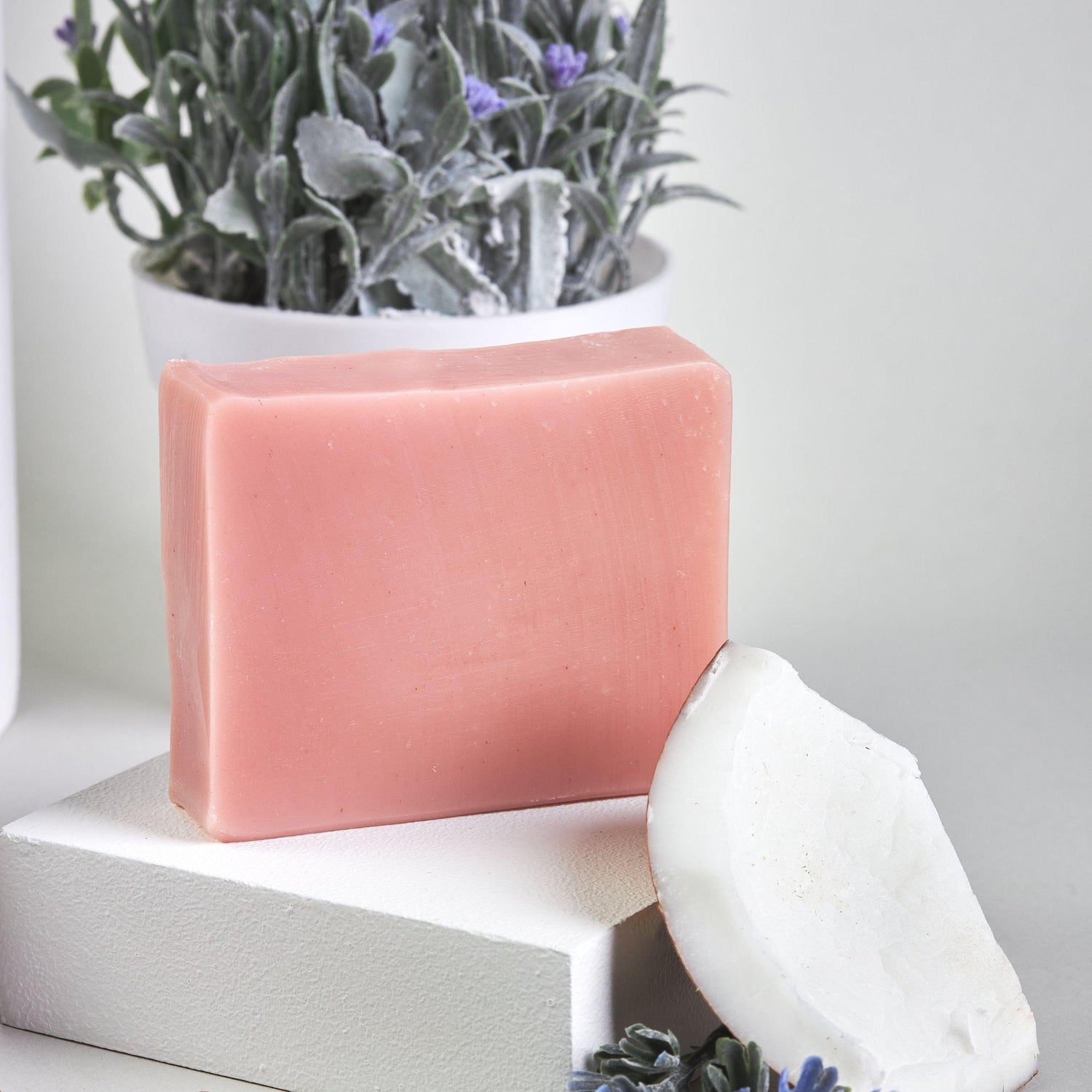 Bonuderm Lavender Bar Soap next to raw lavender sprigs and coconut pieces.