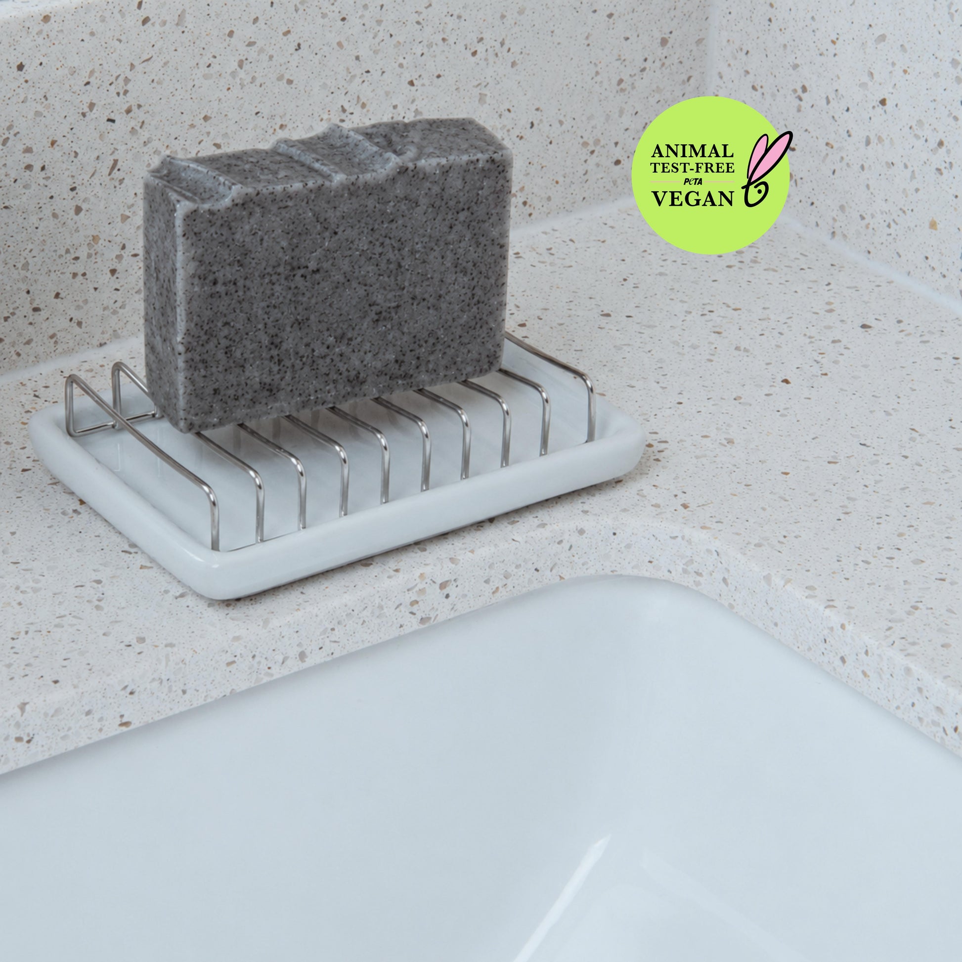 Handmade eucalyptus charcoal soap resting on a soap dish to keep the bar dry between uses and extend its lifespan