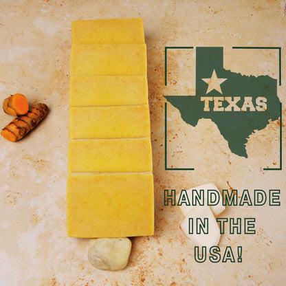 handmade turmeric soap with turmeric root on a textured surface, featuring a Texas map and 'Handmade in the USA!' text.