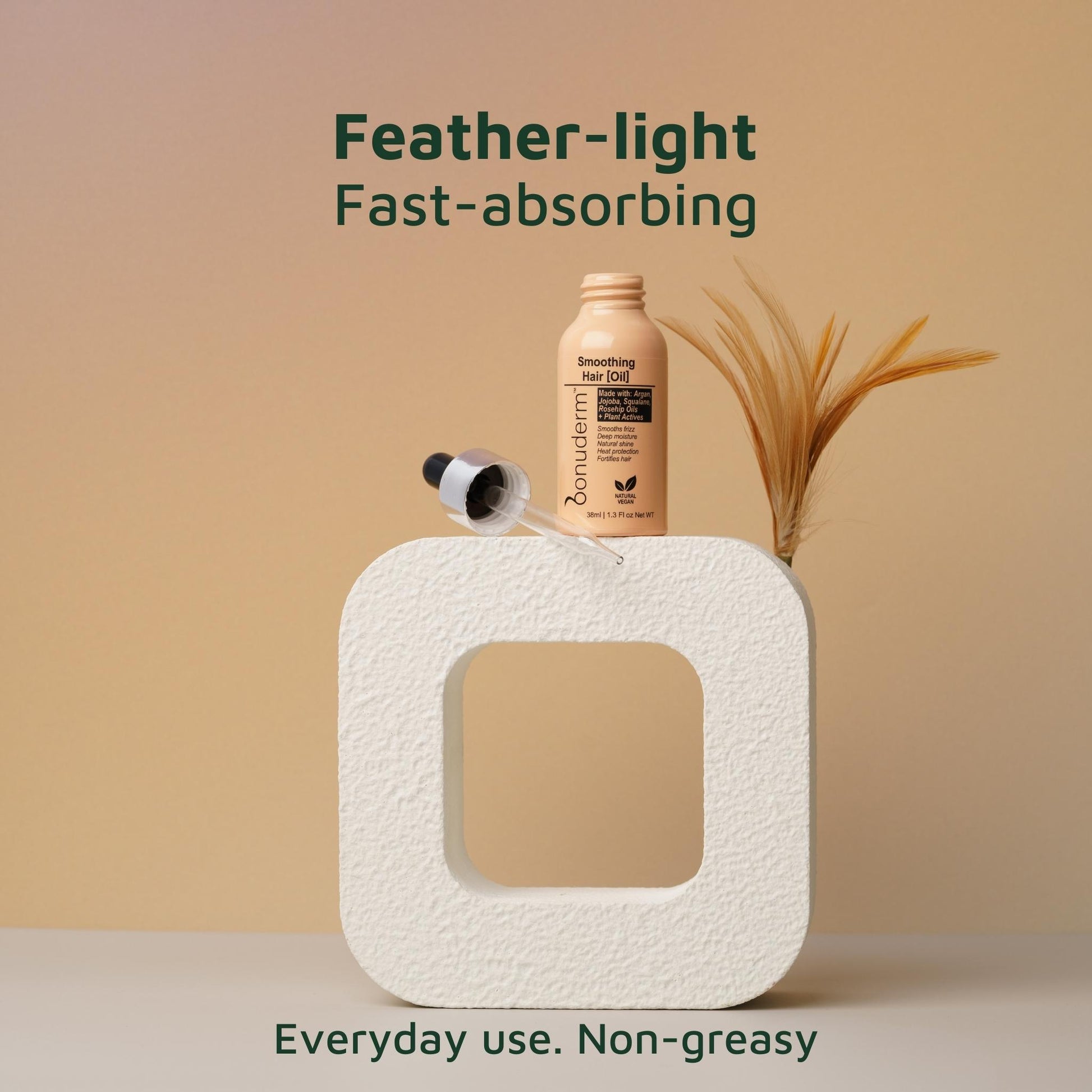 lightweight hair oil moisturizer bottle with a feather on a textured square platform against a beige background