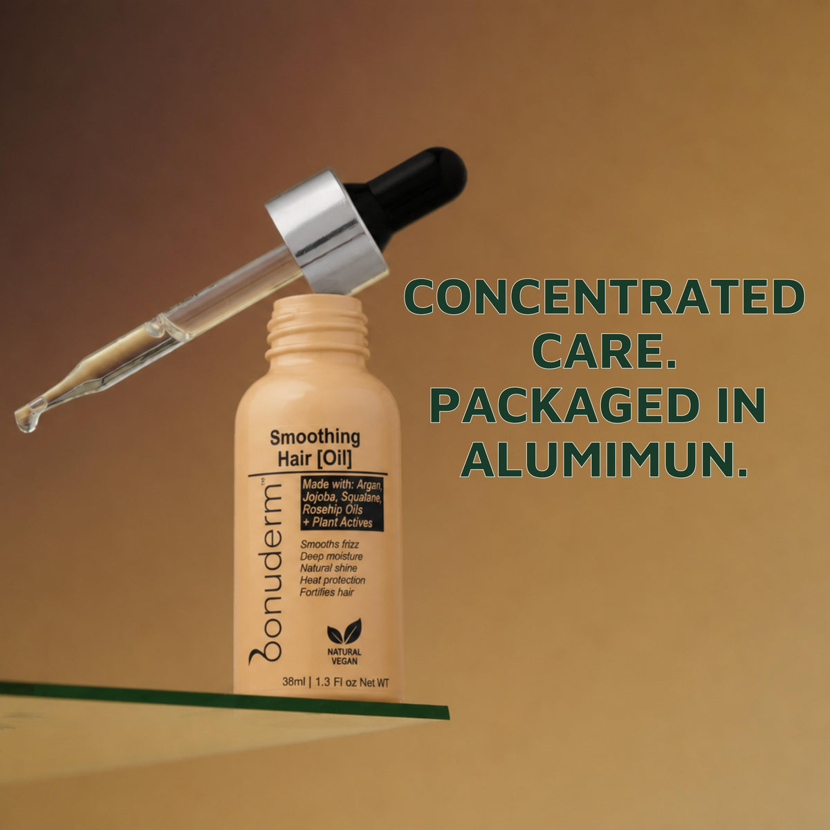bottle of bonuderm moisturizer hair oil with a glass pipette resting on top of it next to a text "concentrated care. packaged in aluminum."