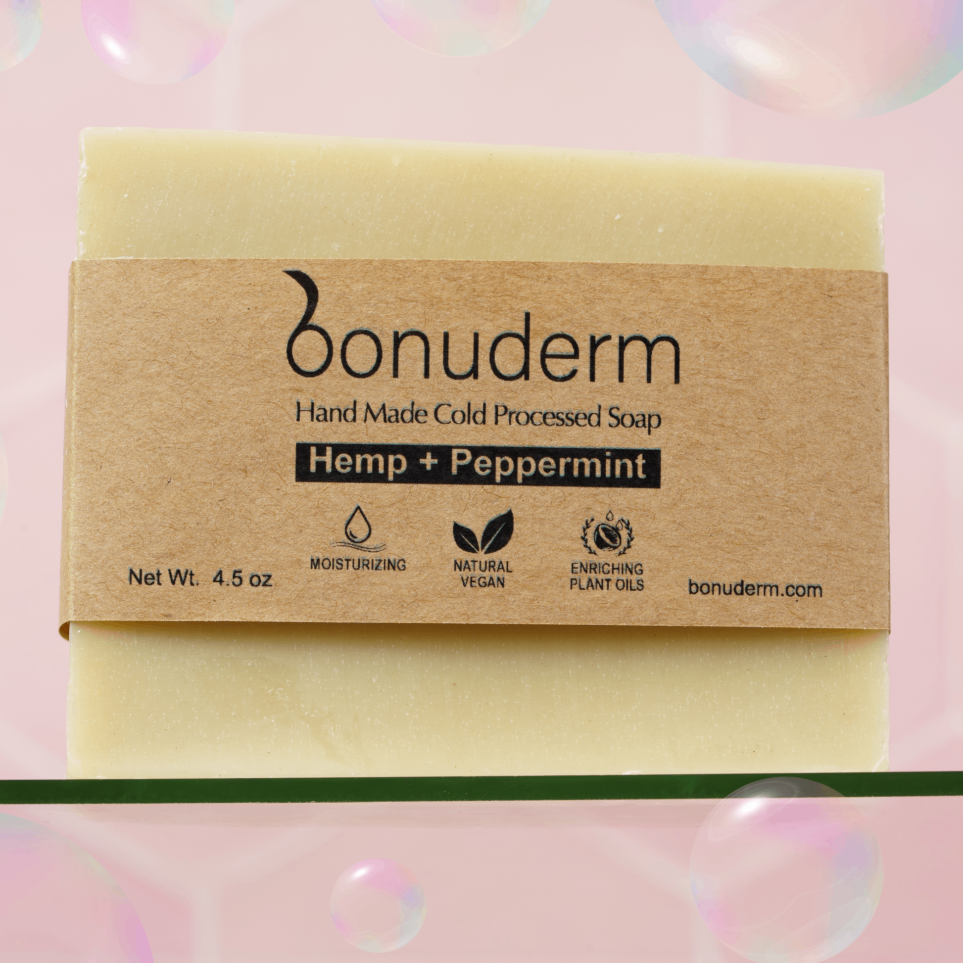 Peppermint bar soap with 'bonuderm' label on a pink background with bubbles with icons indicating moisturizing, vegan, and natural. 
