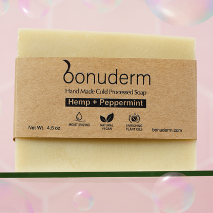 Peppermint bar soap with 'bonuderm' label on a pink background with bubbles with icons indicating moisturizing, vegan, and natural. 