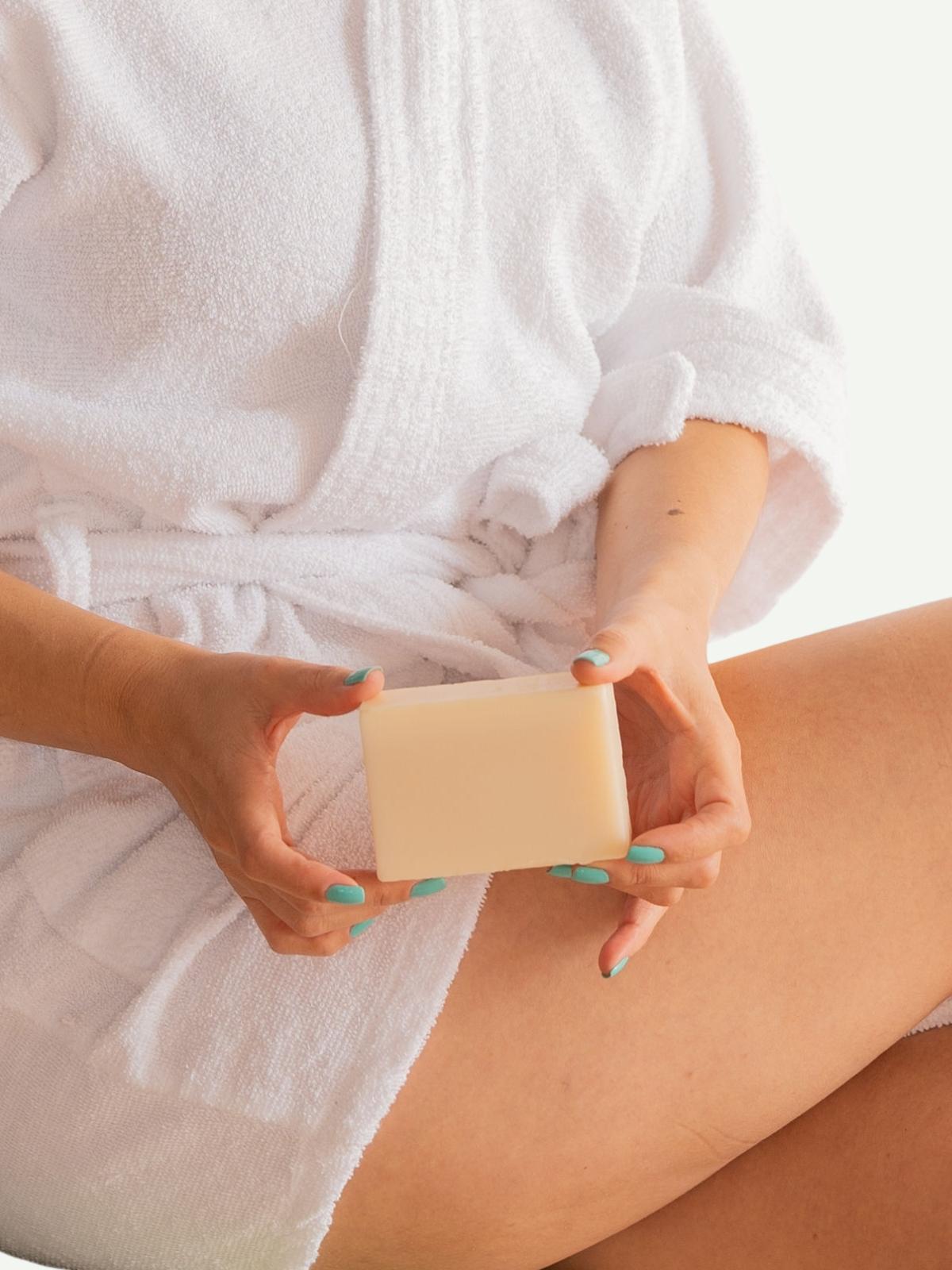Person holding a bar of sensitive skin soap with a blurred background