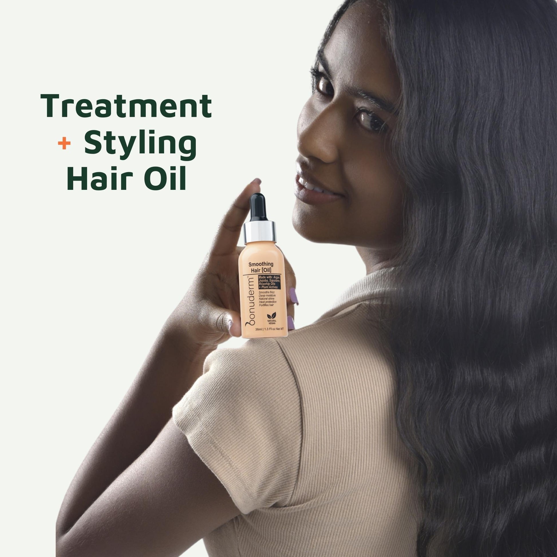 Woman holding a bottle of silicone free hair oil with text 'Treatment + Styling Hair Oil' on a white background