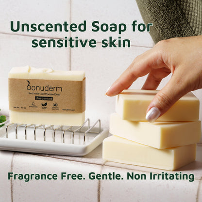 Hand reaching for a bar of unscented soap for sensitive skin with 'bonuderm' branding on a tiled surface.